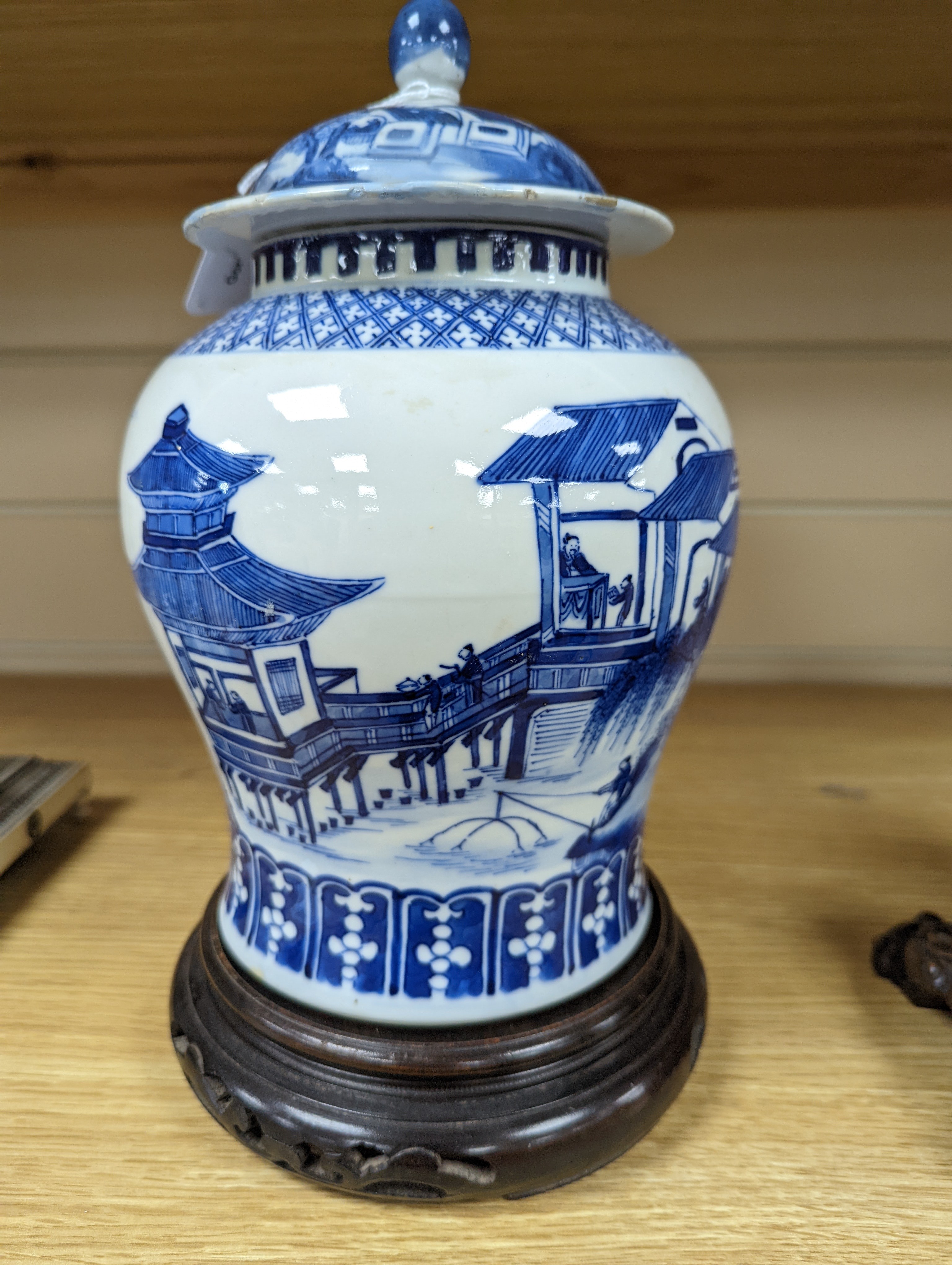 A late 19th / early 20th century Chinese blue and white landscape jar and cover, wood stand 30cm total height